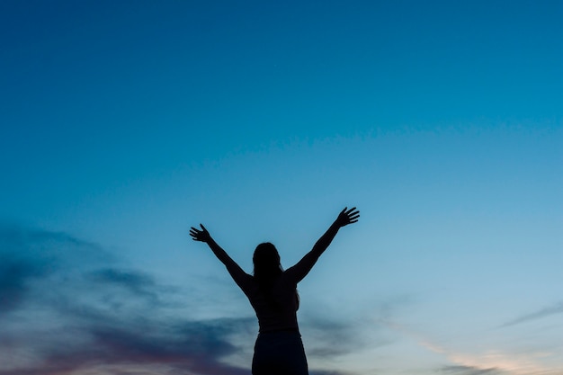 Ángulo bajo de silueta de mujer al atardecer con espacio de copia