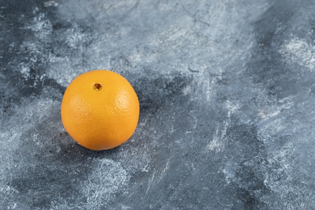 Única naranja sabrosa sobre mesa de mármol.