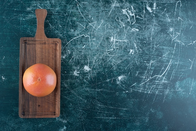 Única naranja sabrosa sobre tabla de madera.