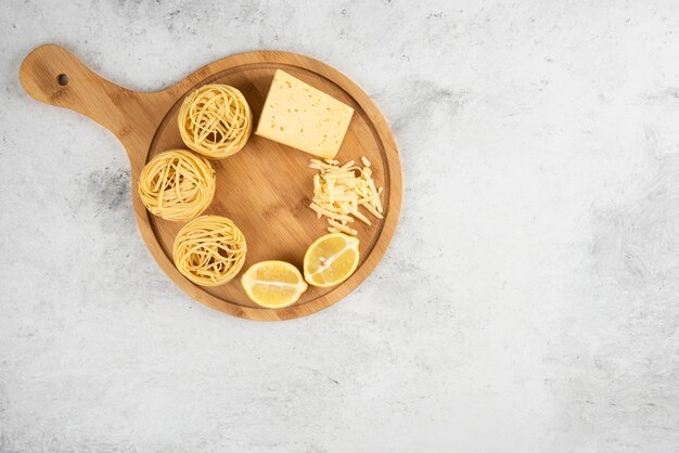 Nidos de espaguetis crudos, tabla de madera de queso lemonnd.