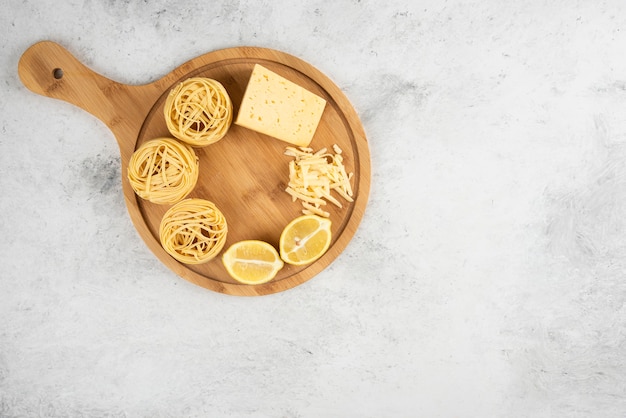 Nidos de espaguetis crudos, tabla de madera de queso lemonnd.