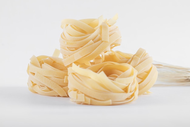 Nidos de tagliatelle secos en blanco.