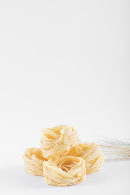 Nidos de tagliatelle secos en blanco.