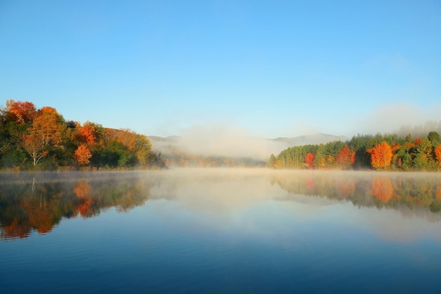 Niebla del lago con follaje otoñal y montañas con reflejo en New England Stowe