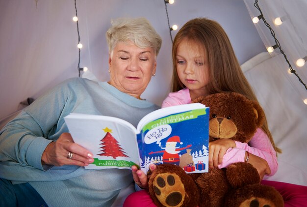 Nieta con abuela viendo un libro de imágenes