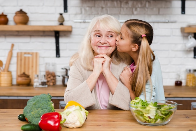 Foto gratuita nieta besando a su abuela en la mejilla