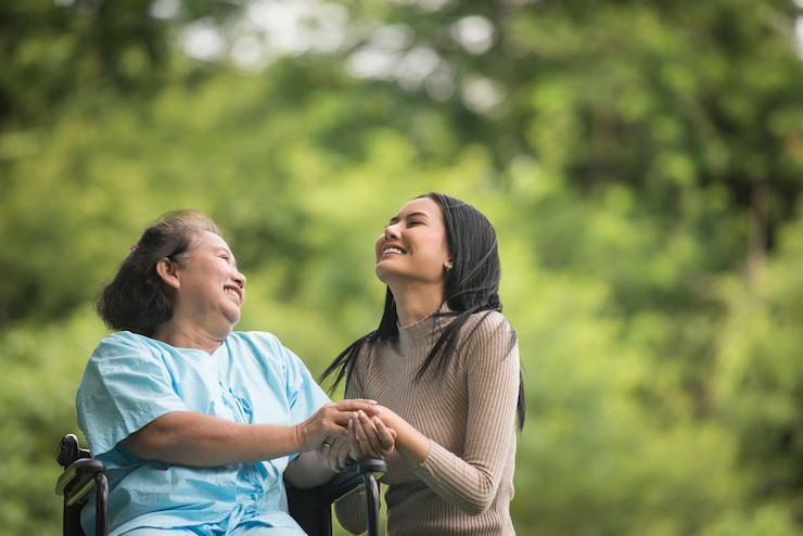 Foto gratuito nieta hablando con su abuela sentada en silla de ruedas, concepto alegre, familia feliz