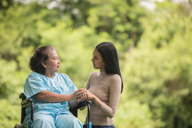 Nieta hablando con su abuela sentada en silla de ruedas, concepto alegre, familia feliz