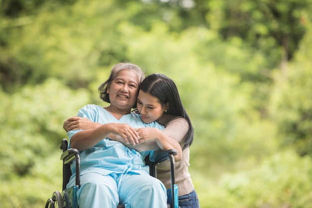 Nieta hablando con su abuela sentada en silla de ruedas, concepto alegre, familia feliz