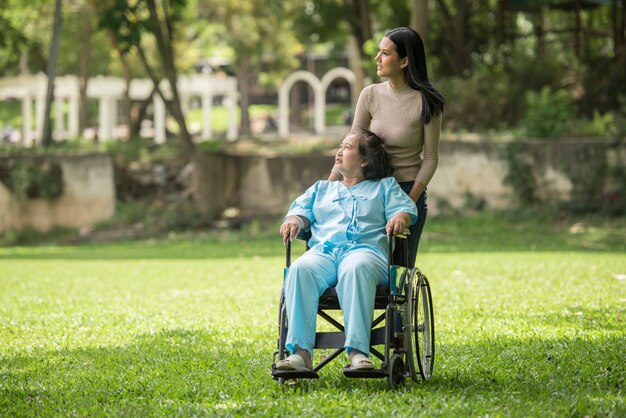 Nieta hablando con su abuela sentada en silla de ruedas, concepto alegre, familia feliz