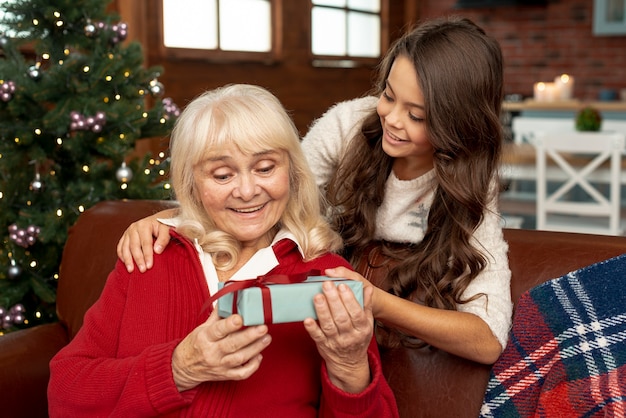 Nieta de tiro medio que le ofrece un regalo a la abuela