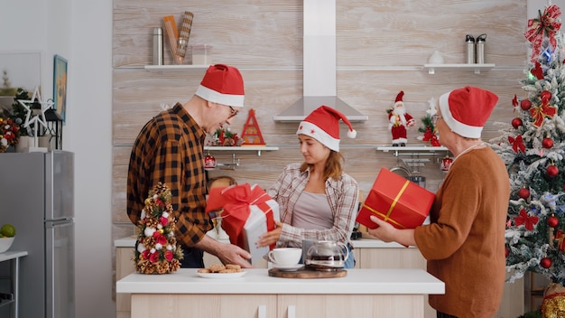 Nieta trayendo envoltura de regalo presente sorpresa a los abuelos celebrando la Navidad