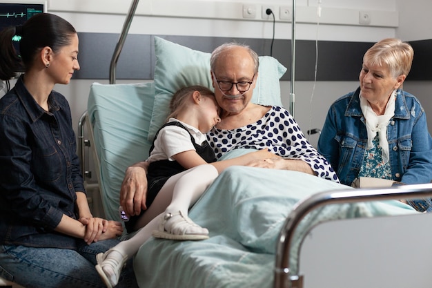 Nieto cariñoso abrazando a abuelos ancianos enfermos mostrando amor