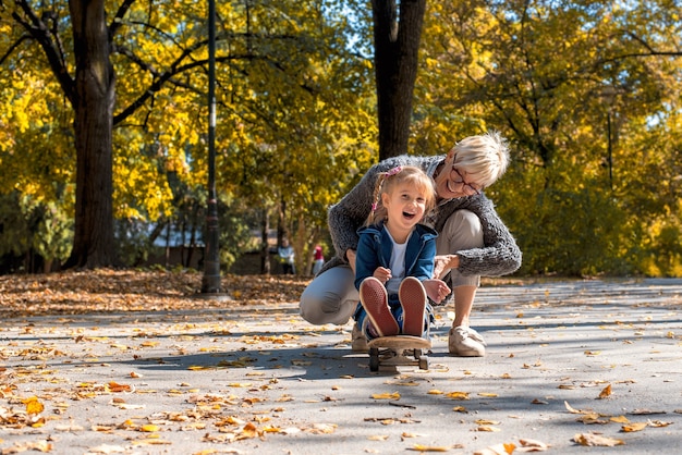 Foto gratuita nieto femenino sonriente jugando con su abuelo en el parque