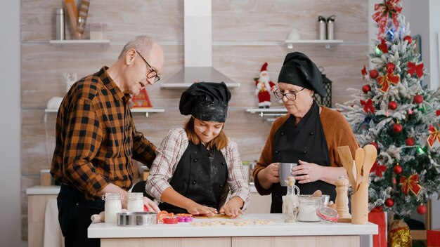 Nieto mostrando a los abuelos cómo usar la forma de las cookies