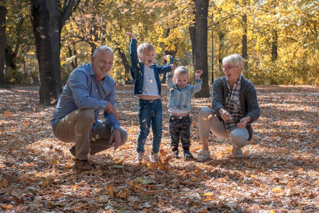 Nietos y abuelos tirando hojas en el parque y pasando tiempo juntos