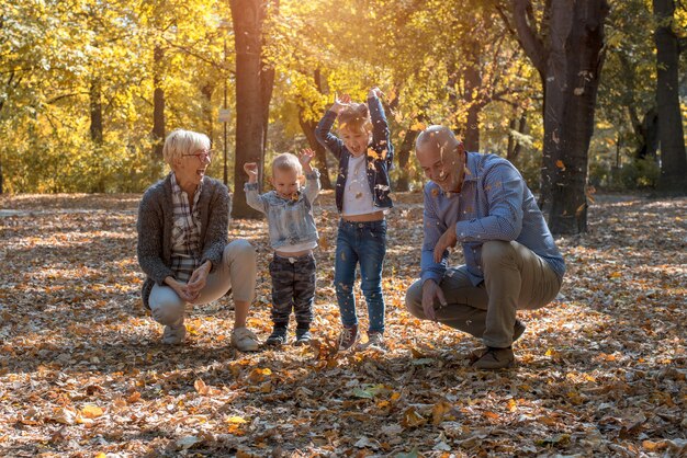Nietos y abuelos tirando hojas en el parque y pasando tiempo juntos