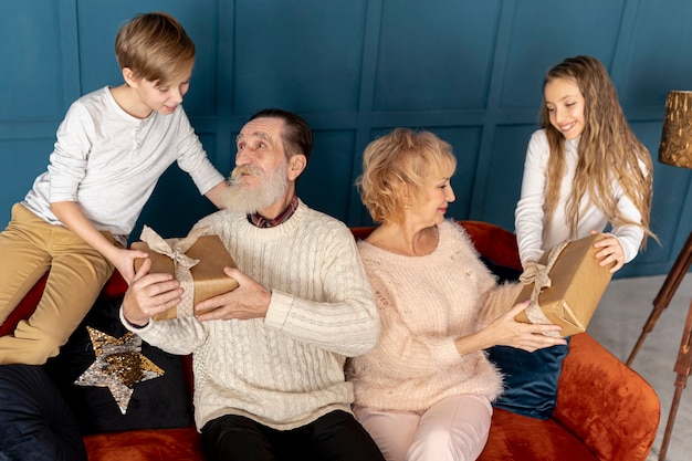 Foto gratuita nietos de vista frontal dando regalos a sus abuelos