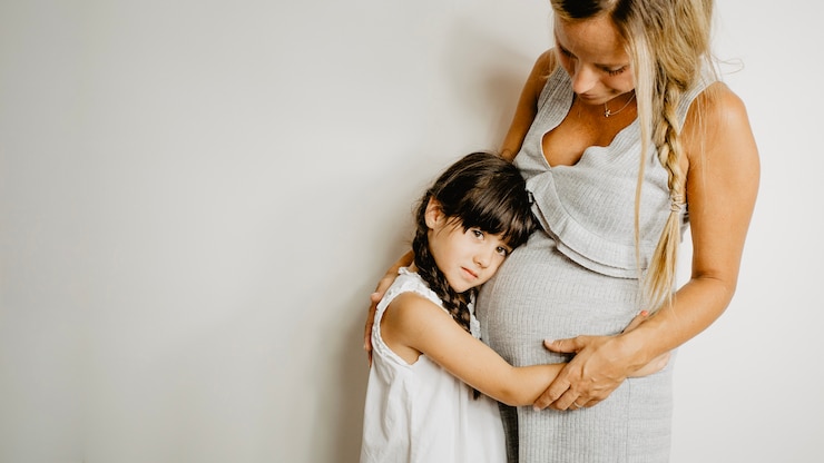 Foto gratuito niña abrazando a la madre embarazada