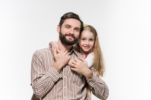 Niña abrazando a su padre sobre un blanco