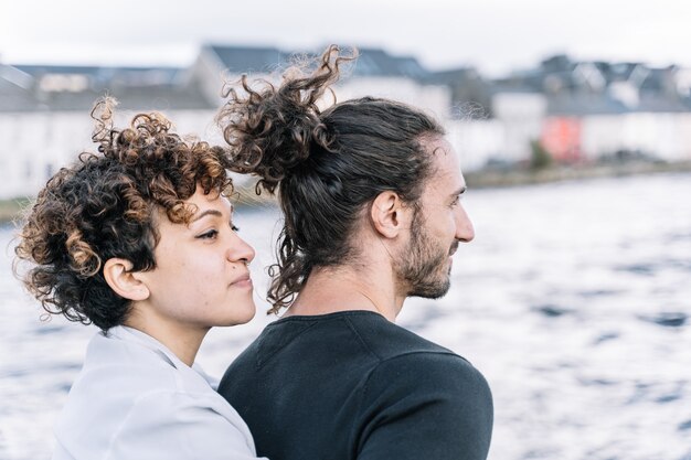 Niña abrazando a su pareja con el mar fuera de foco