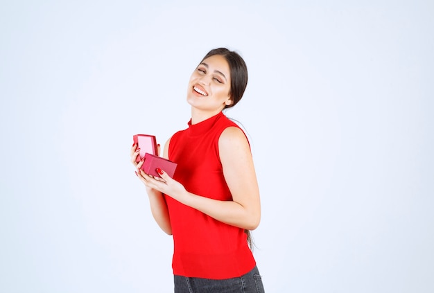 La niña abrió una caja de regalo roja y se siente feliz.