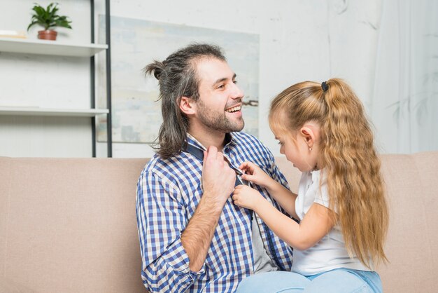 Niña abrochando camisa de su padre