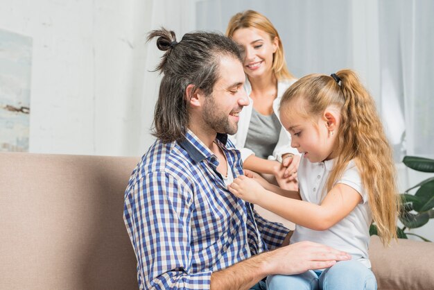 Niña abrochando camisa de su padre