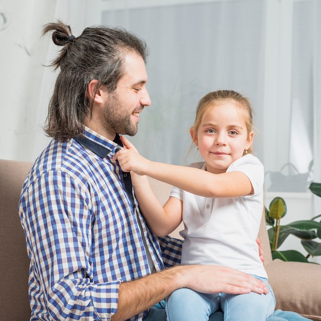 Niña abrochando camisa de su padre