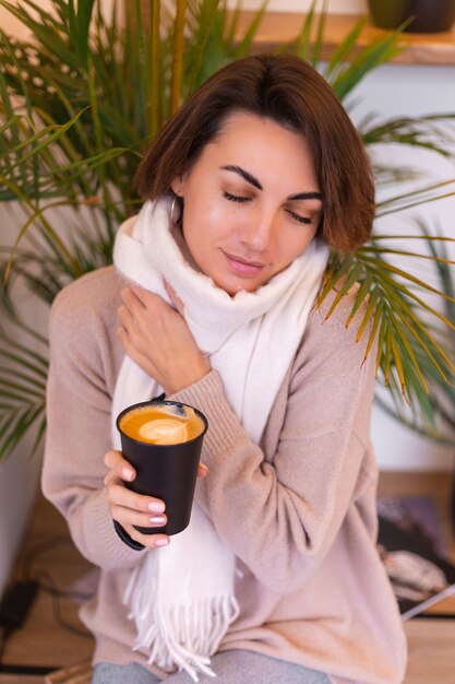 Una niña en un acogedor café se calienta con una taza de café caliente.