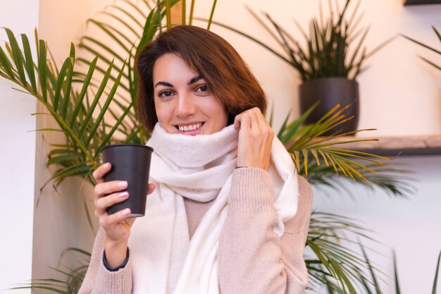 Una niña en un acogedor café se calienta con una taza de café caliente.