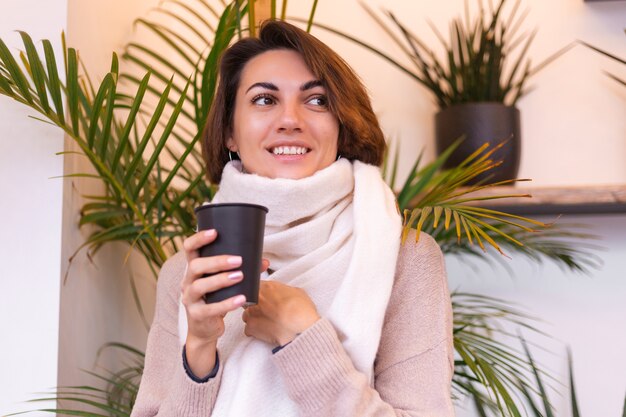 Una niña en un acogedor café se calienta con una taza de café caliente.