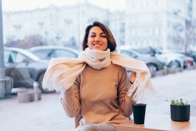 Foto gratuita una niña en un acogedor café se calienta con una taza de café caliente.