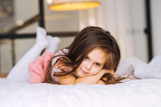 Niña acostada en la cama mirando a otro lado.