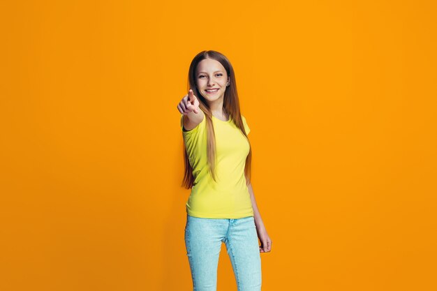 La niña adolescente feliz apuntando a usted, retrato de primer plano de media longitud