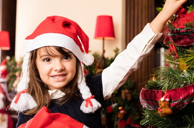 Niña adorable al lado de un árbol de navidad