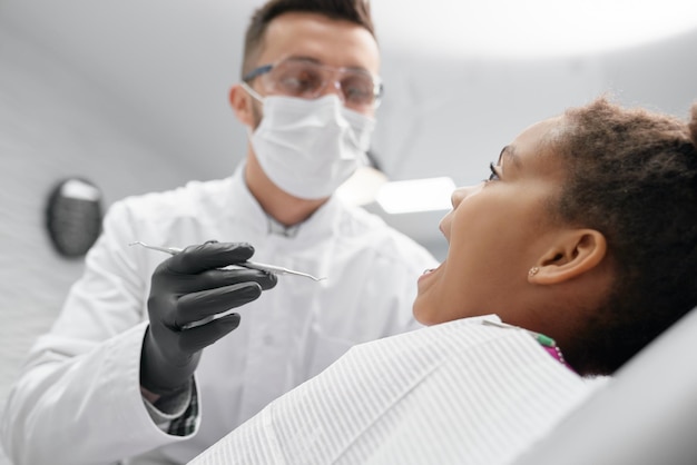 Niña africana acostada en la silla del dentista con la boca abierta