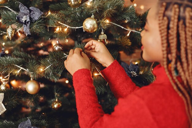 Niña africana en adornos navideños / Mujer con un suéter rojo. Concepto de año nuevo.