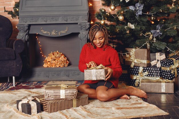 Niña africana en adornos navideños / Mujer con un suéter rojo. Concepto de año nuevo.