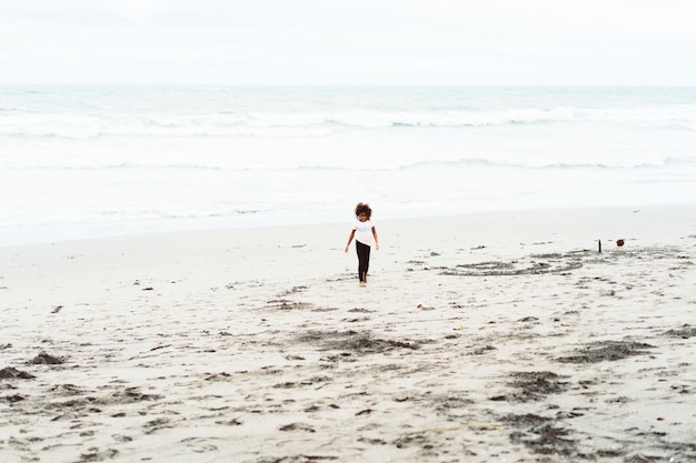 Niña africana divirtiéndose en la playa de arena