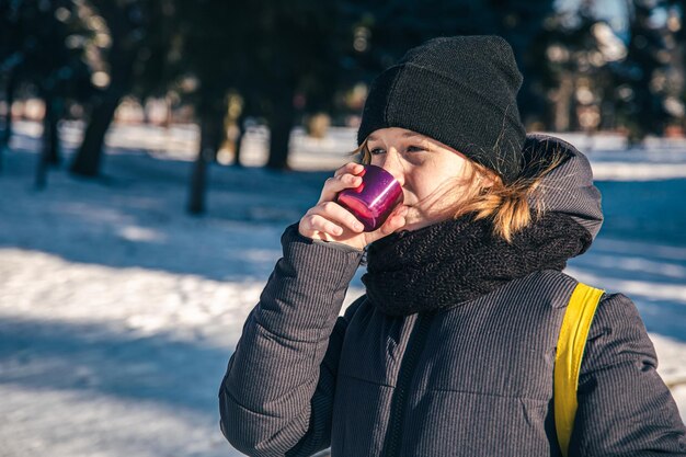 Una niña afuera con termo en un frío día de invierno.