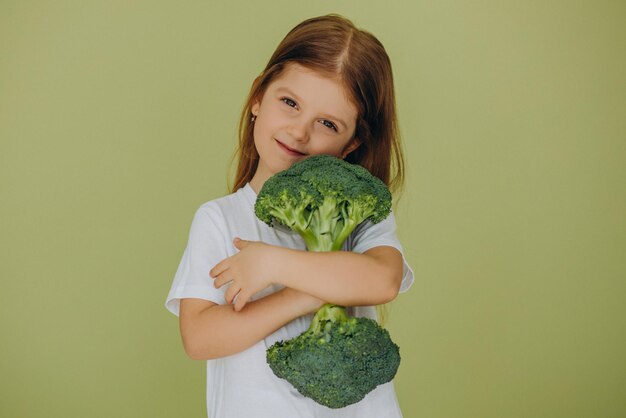 Niña aislada sosteniendo brócoli crudo verde