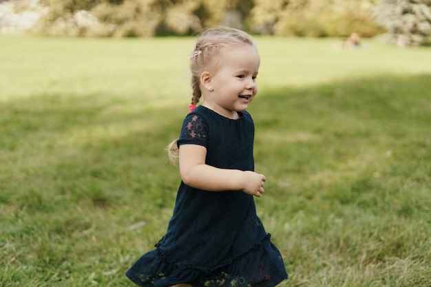 Niña alegre corriendo sobre la hierba verde