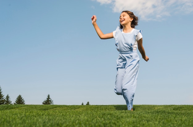 Niña alegre corriendo sobre la hierba