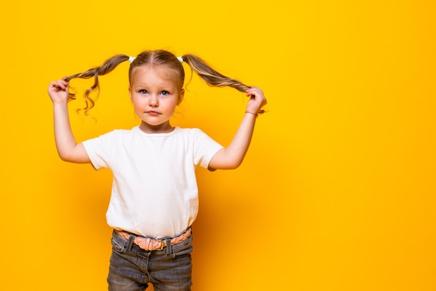 Foto gratuita niña alegre jugando con el pelo posando aislado en la pared amarilla