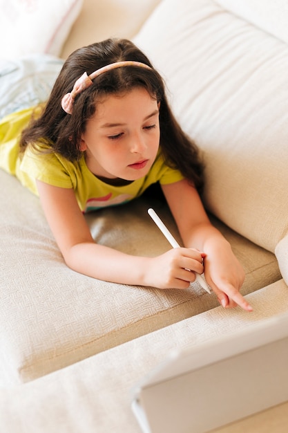 Niña de alto ángulo apuntando a su tableta