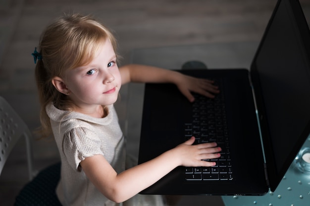 Niña de alto ángulo jugando en la computadora portátil