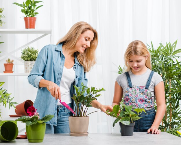 Niña de alto ángulo viendo a mamá plantar flores