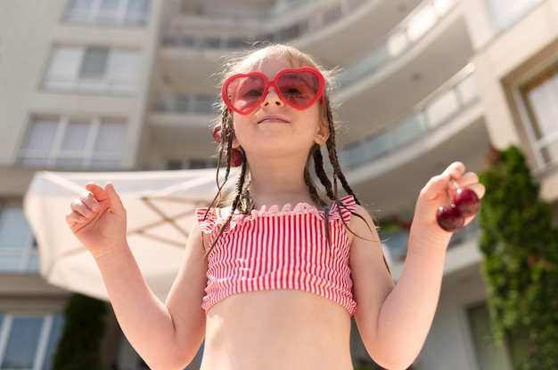 Niña de ángulo bajo con cerezas