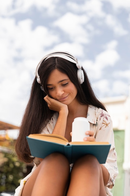 Foto gratuita niña de ángulo bajo leyendo al aire libre